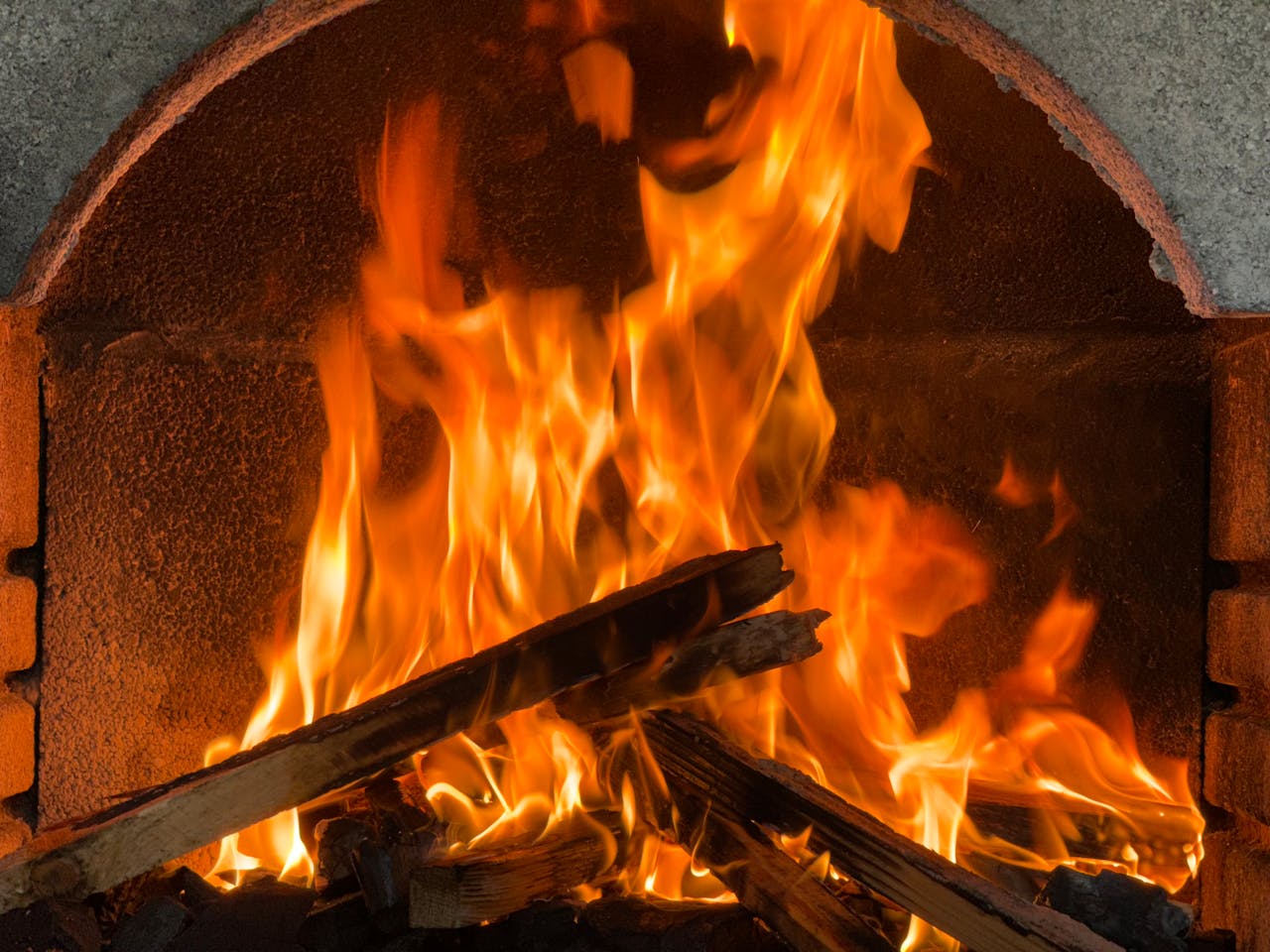 Close-up of vibrant flames in a brick fireplace, evoking warmth and coziness.