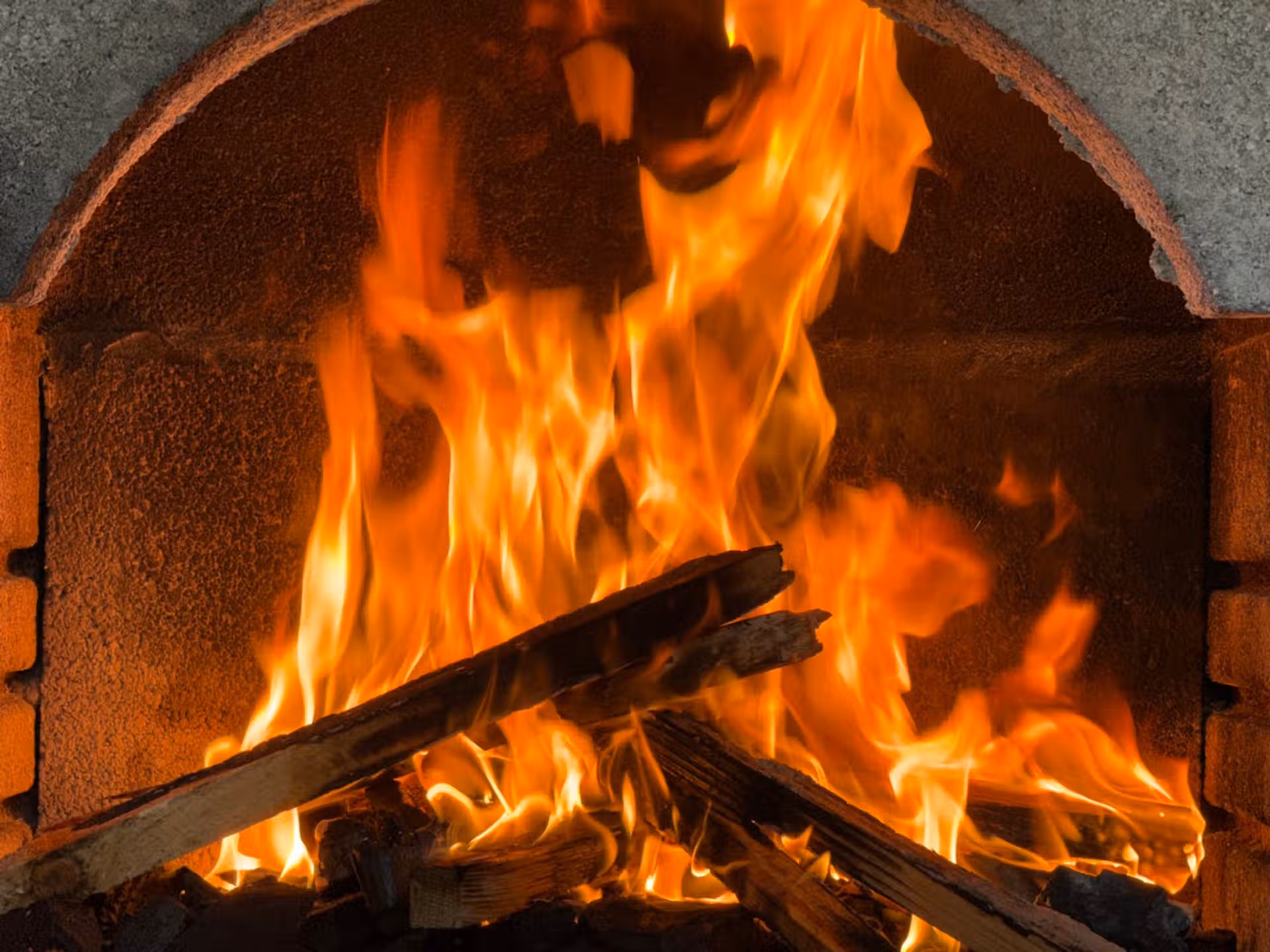 Close-up of vibrant flames in a brick fireplace, evoking warmth and coziness.
